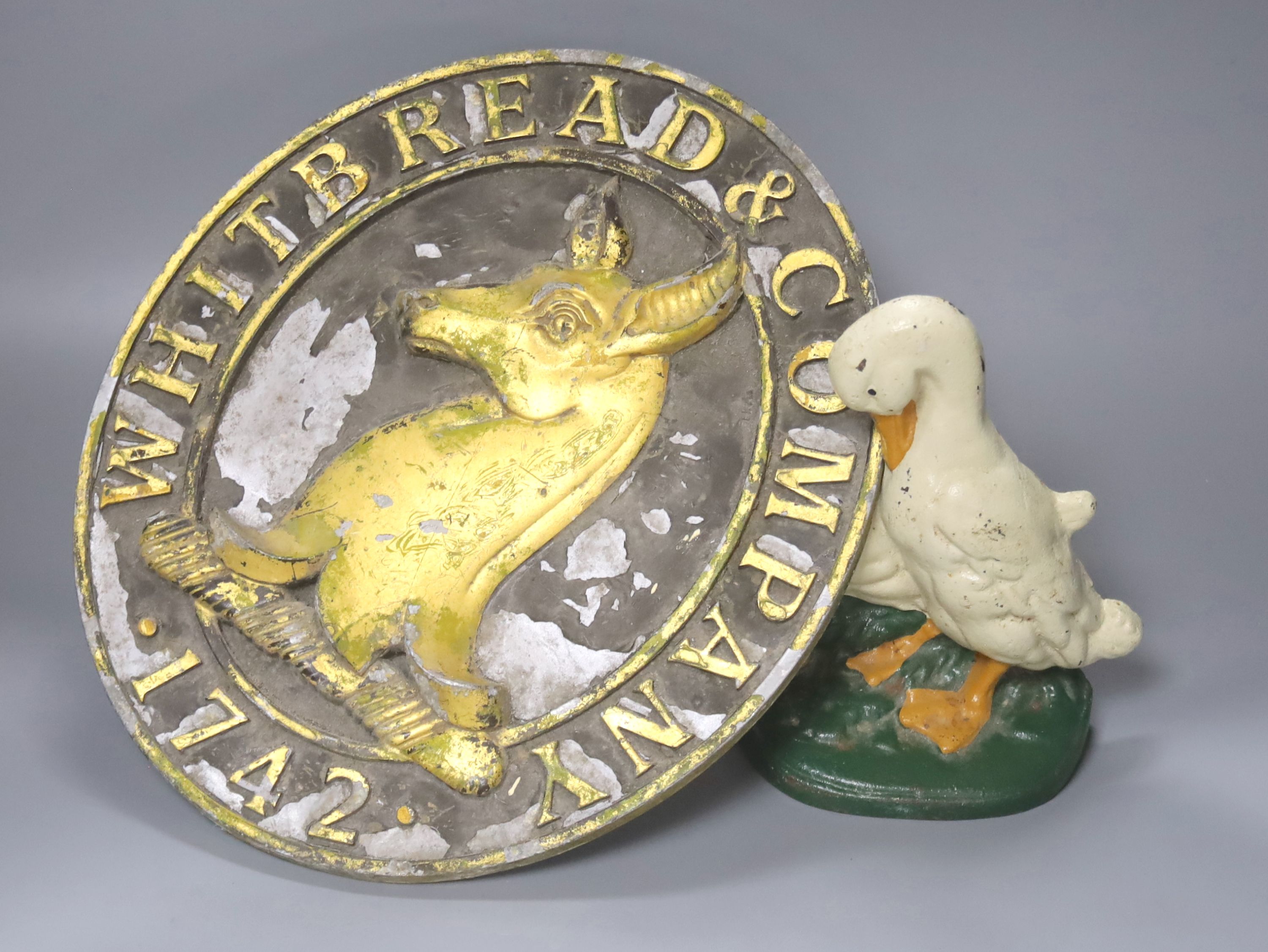 A vintage Whitbread & Company oval plaque, length 33cm, and a painted goose door stop